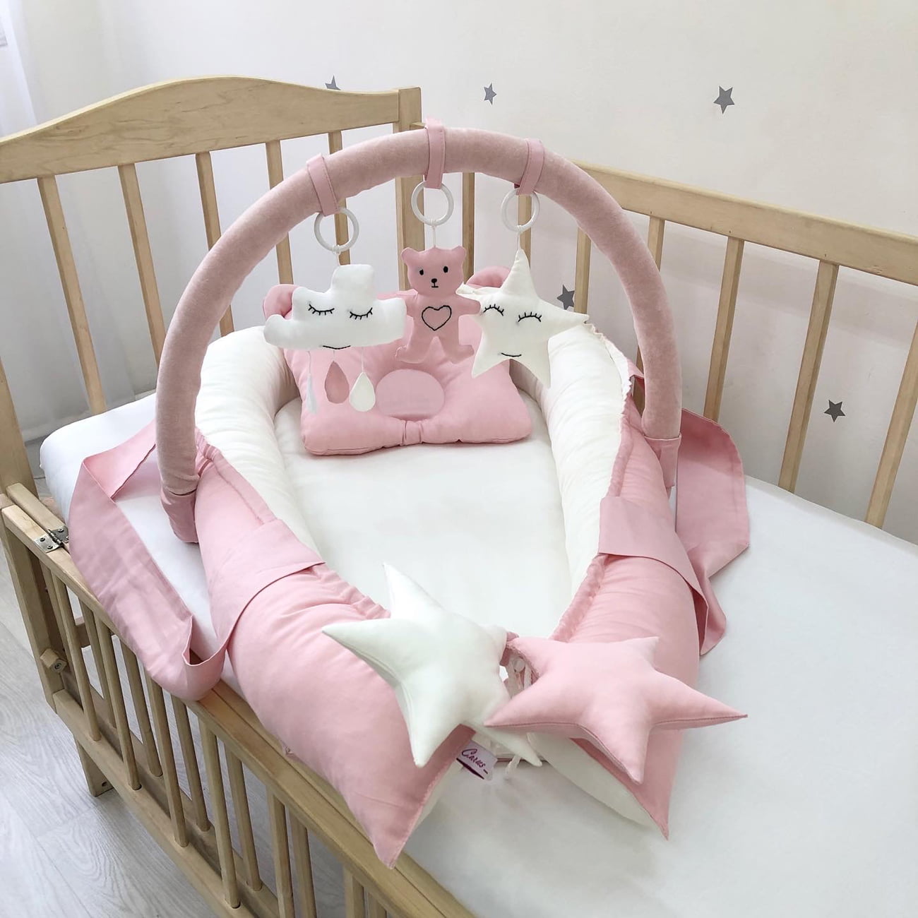 Dusty rose baby nest and arc with mini-toys.