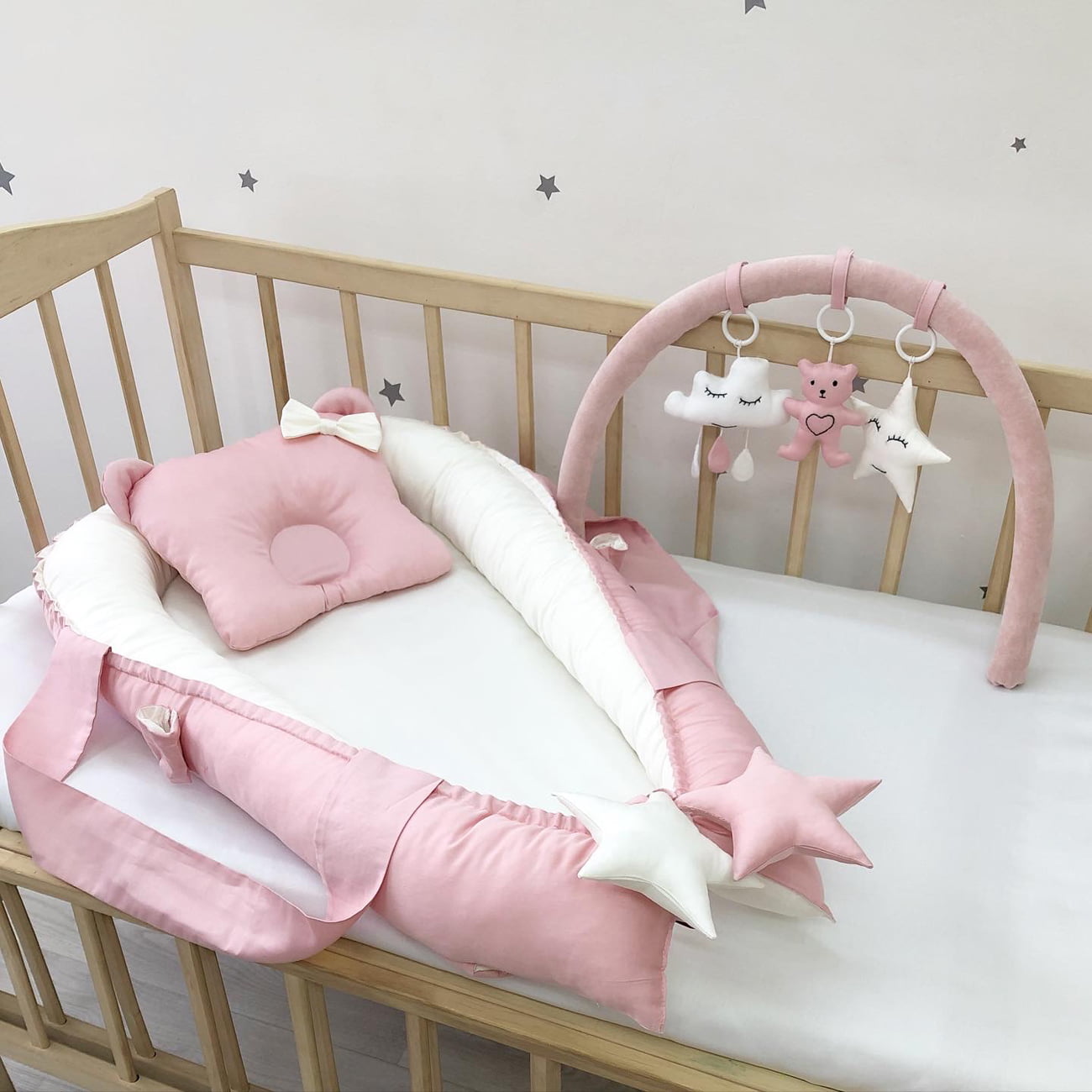 Dusty rose baby nest and arc with mini-toys.